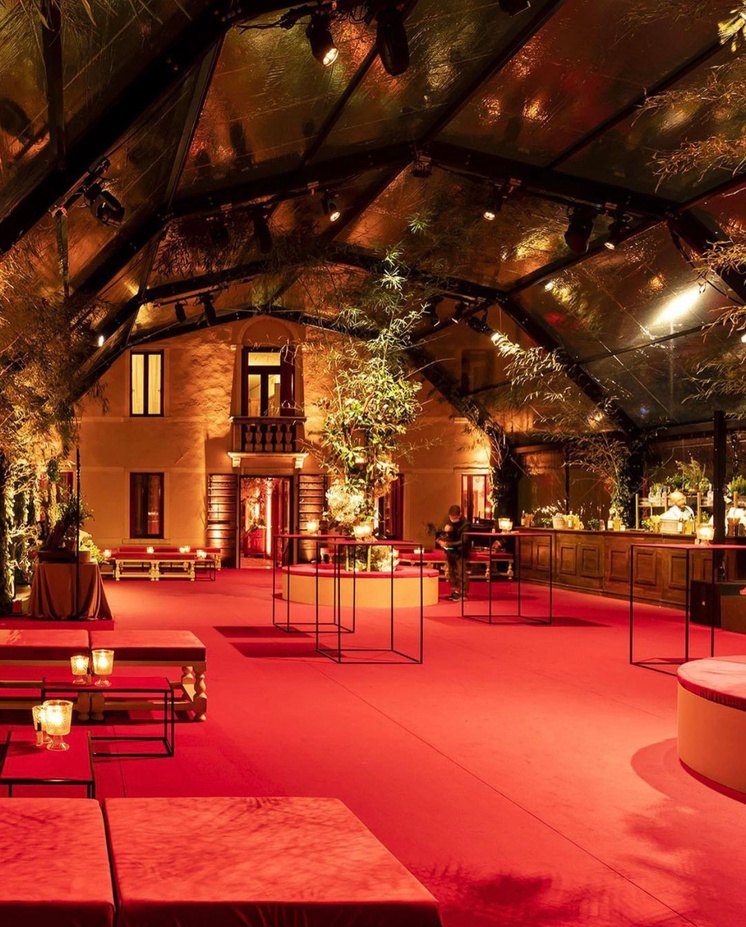 Grande area lounge in rosso sotto una copertura trasparente addossata all'edificio
