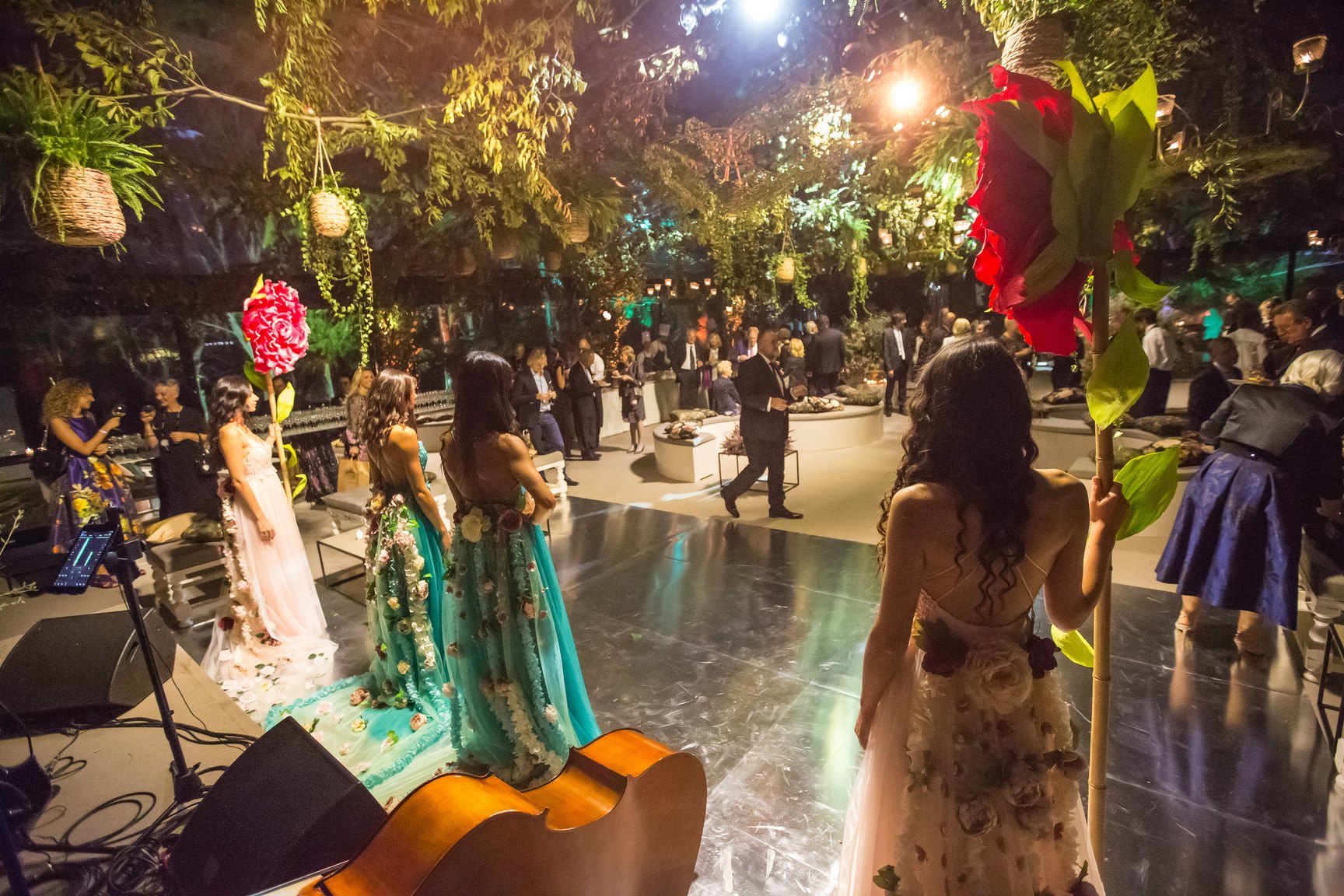 Festa serale in un giardino d'inverno vista dal palco, con l'allestimento della band in primo piano e gli ospiti sul pavimento lucido