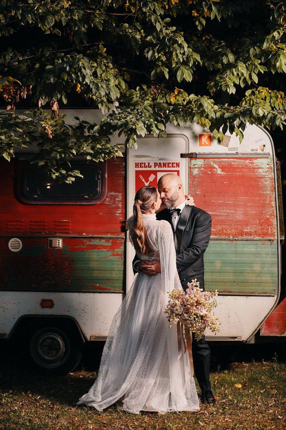 Gli sposi si baciano davanti a un vecchio camper
