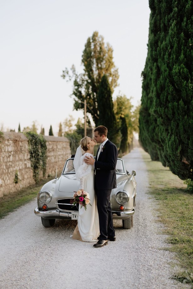 Gli sposi e l'auto d'epoca nel viale di cipressi